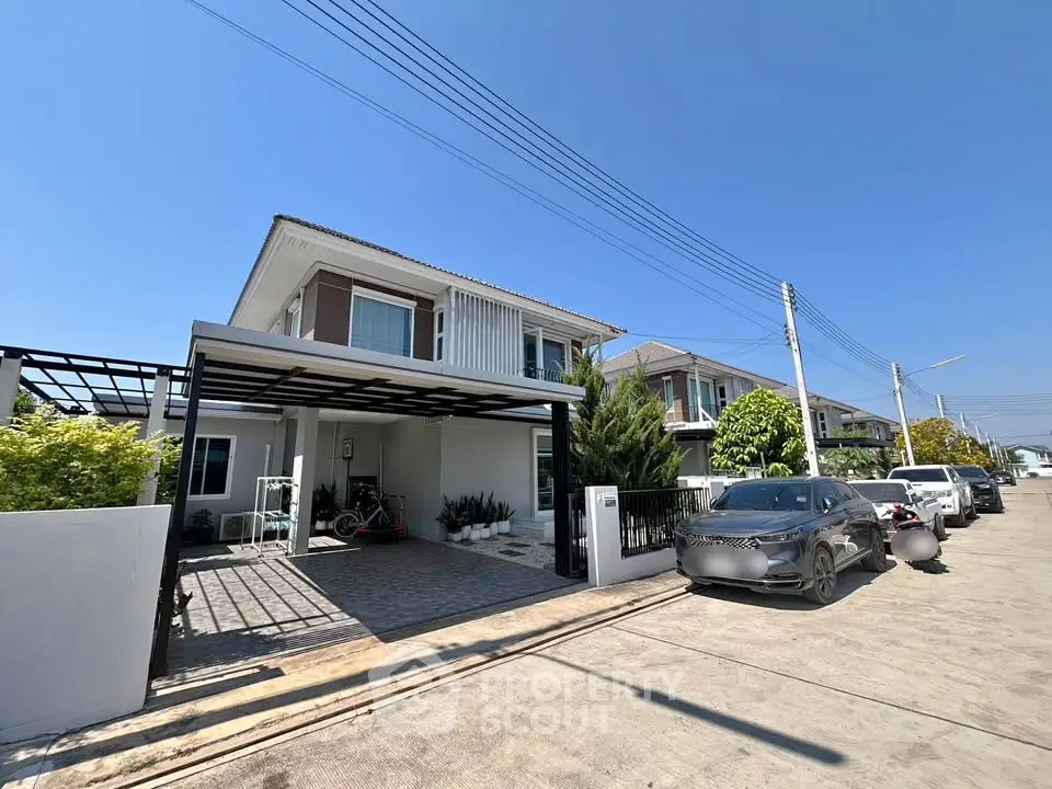 Modern suburban house with driveway and parked cars in a sunny neighborhood.