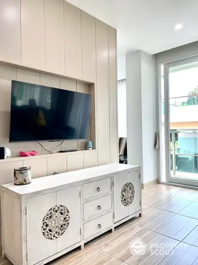 Bright and airy living space with modern built-in wall unit for entertainment, sleek tiled flooring, and access to a sunlit patio through sliding glass doors.