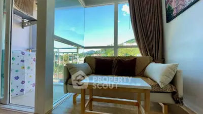 Cozy living room with a view, featuring a comfortable sofa and coffee table near a glass balcony.