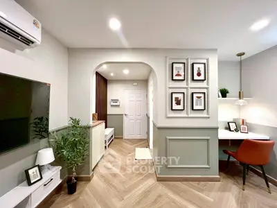 Modern living room with stylish decor and workspace, featuring herringbone flooring and elegant lighting.