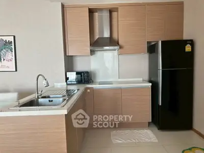 Modern kitchen with wooden cabinets, stainless steel sink, and black refrigerator in a stylish apartment.
