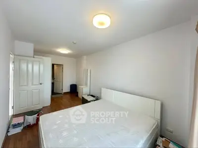 Spacious bedroom with wooden flooring and modern lighting