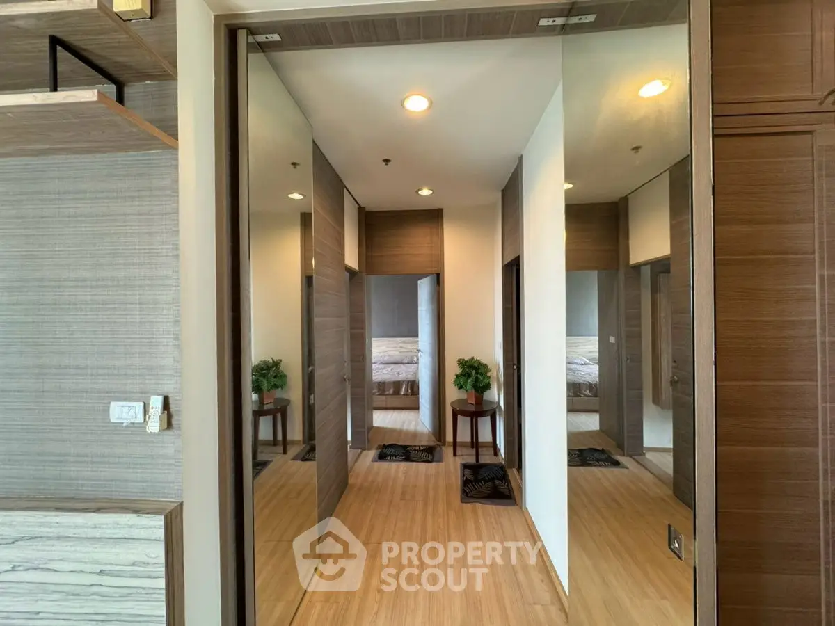 Modern hallway with wooden flooring and mirrored walls in a stylish apartment.