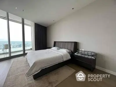 Spacious bedroom with large windows offering ample natural light and a stunning city view, featuring a modern bed and elegant furnishings.