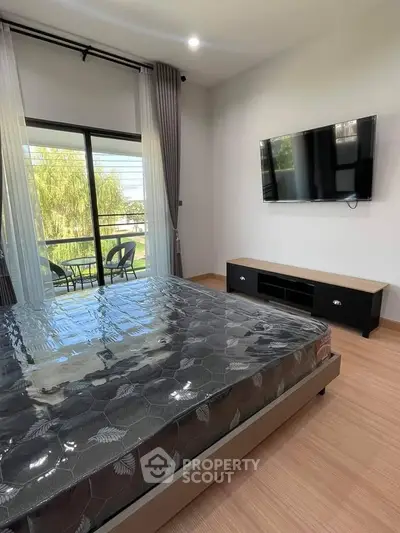 Modern bedroom with balcony view and wall-mounted TV in stylish apartment.