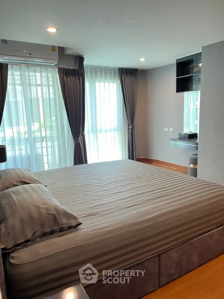 Spacious bedroom with large windows and modern decor in a stylish apartment.