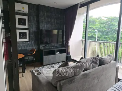 Modern living room with stylish decor and spacious balcony overlooking greenery.