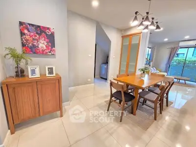 Modern dining area with wooden table and chairs, bright lighting, and stylish decor in a spacious open-plan layout.