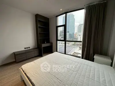 Modern bedroom with city view and large windows in high-rise apartment