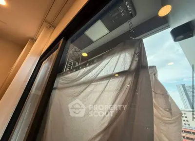 Modern apartment balcony with city view and covered furniture, showcasing urban living.