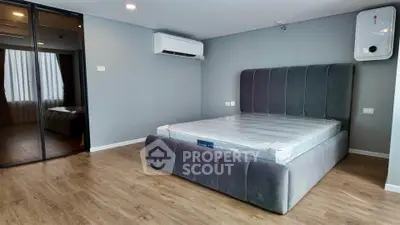 Modern bedroom with sleek design, featuring a plush bed, mirrored closet, and air conditioning.