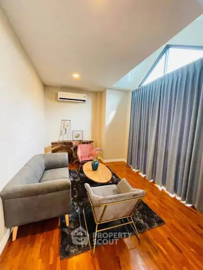 Stylish living room with modern furniture and large window draped with elegant curtains.