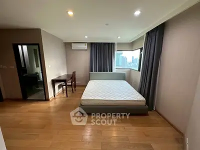 Spacious bedroom with city view, featuring a comfortable bed and study area, perfect for urban living.
