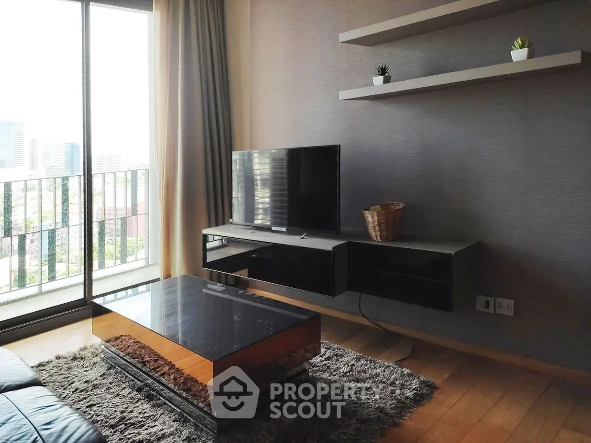 Modern living room with sleek TV stand, glass coffee table, and city view balcony.
