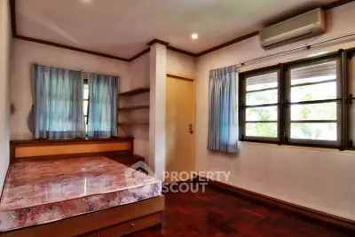 Cozy bedroom with wooden flooring and natural light, featuring a built-in shelf and air conditioning.