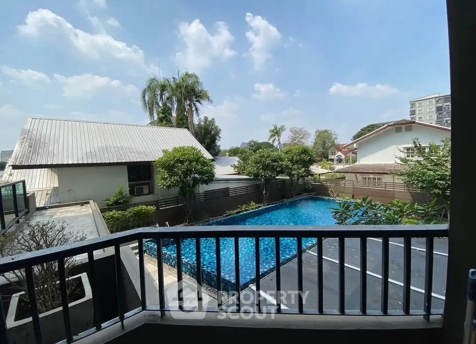 Charming residential view with pool and lush greenery under a clear blue sky.