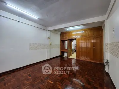 Spacious room with wooden flooring and built-in cabinets, ideal for versatile living space.