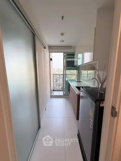 Modern kitchen with balcony view, featuring sleek appliances and ample natural light.