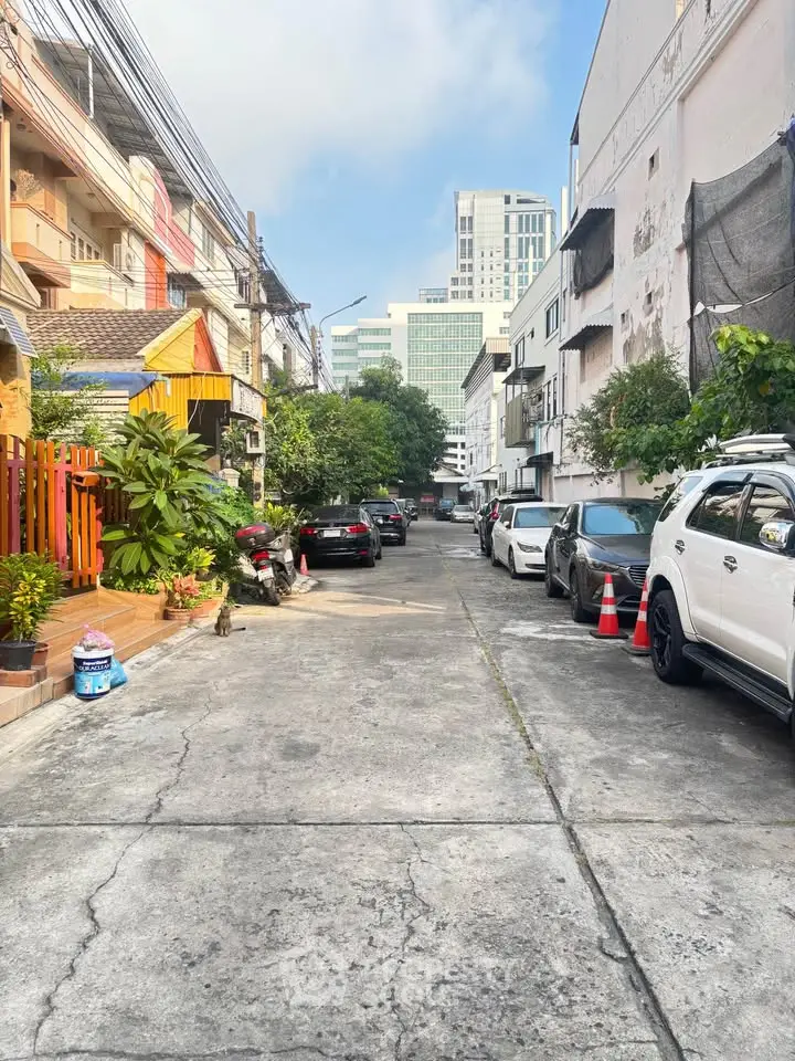 Charming urban street view with parked cars and lush greenery, ideal for city living enthusiasts.