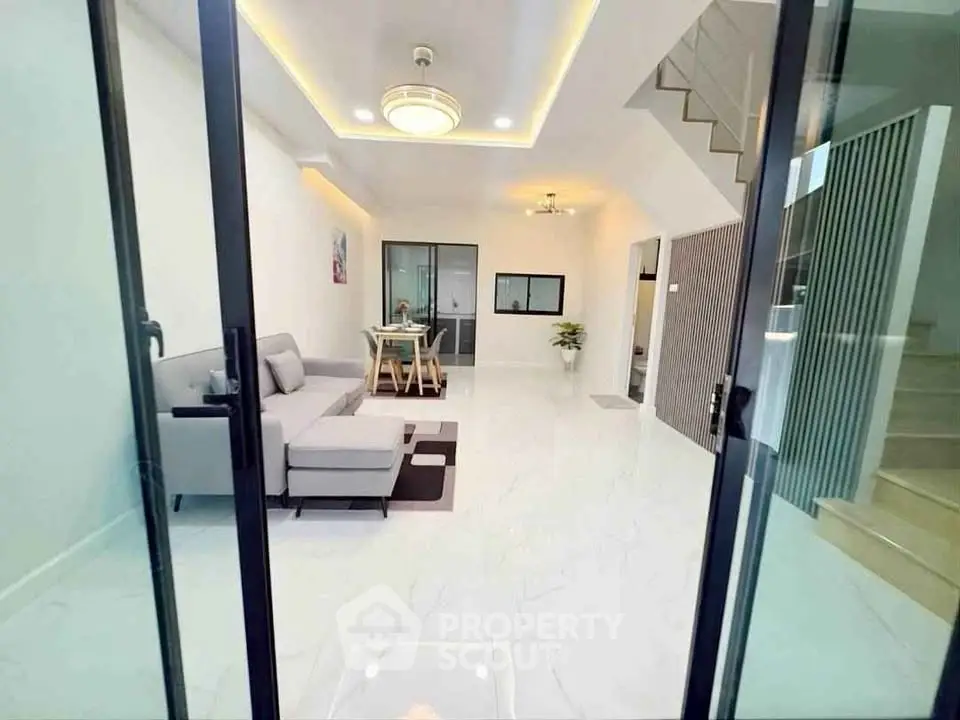 Modern living room with sleek design and open layout, featuring a cozy gray sofa and elegant dining area.