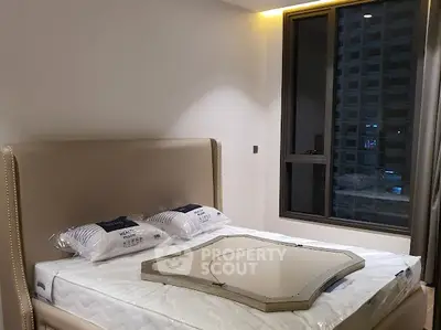 Modern bedroom with large window and stylish bed in high-rise apartment.