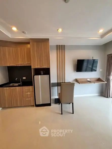 Modern studio apartment with sleek kitchen and wall-mounted TV