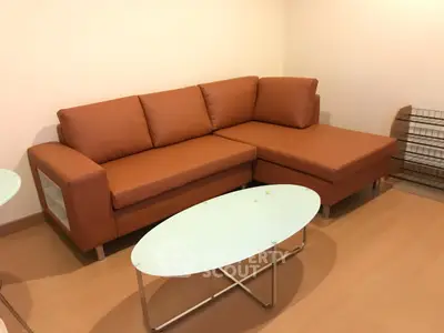 Cozy living room with modern brown leather sectional sofa and sleek glass coffee table.