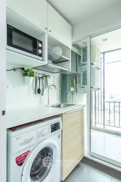 Modern laundry area with washing machine and balcony view in a bright apartment.