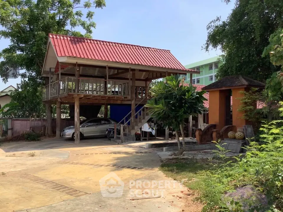 Charming elevated wooden house with red roof and spacious outdoor area, perfect for serene living.