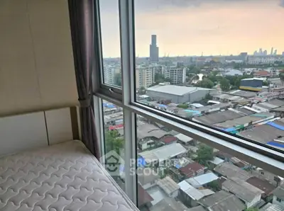 High-rise bedroom with panoramic city view through large windows, showcasing urban skyline.