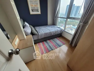 Cozy bedroom with city view, featuring a single bed, wooden flooring, and large windows for natural light.