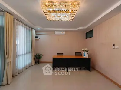 Elegant office space with modern chandelier and large windows for natural light.