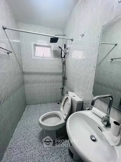 Compact bathroom with modern fixtures and tiled walls, featuring a shower and toilet.