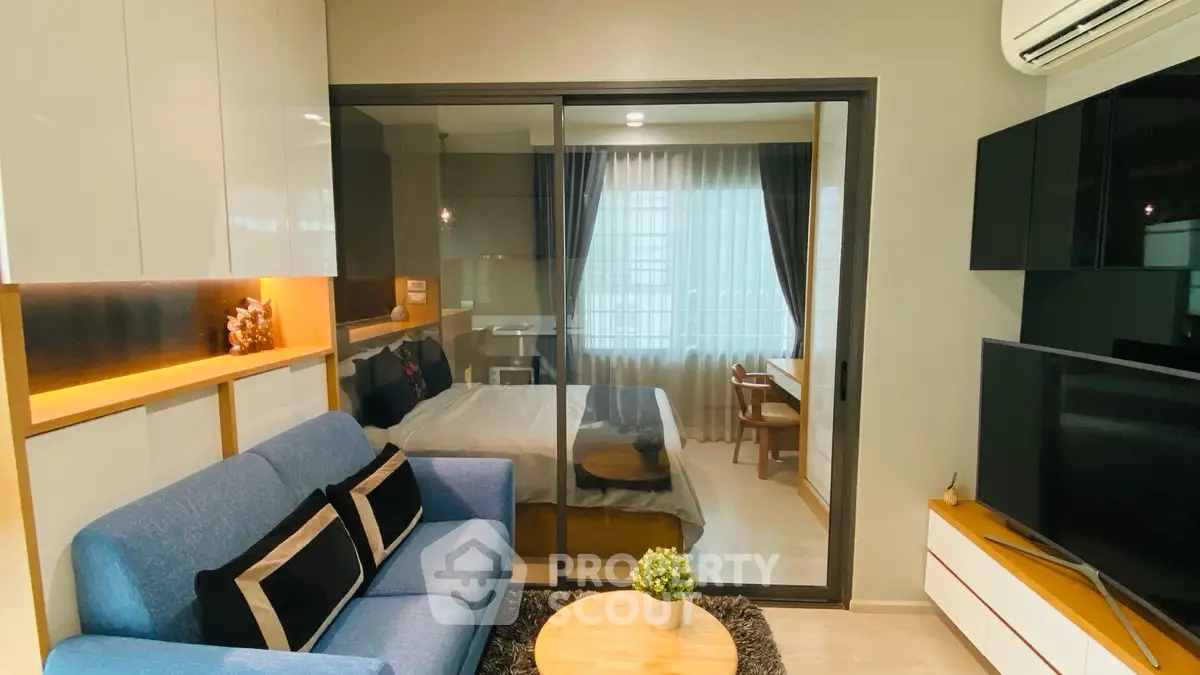 Modern studio apartment with cozy living area and glass partitioned bedroom.