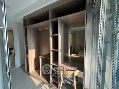 Modern bedroom with built-in wooden wardrobe and study desk, featuring sleek design and ample natural light.