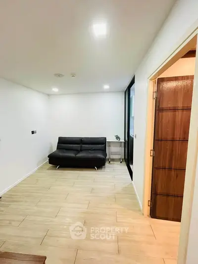 Modern living room with sleek black sofa and wooden flooring, perfect for cozy gatherings.