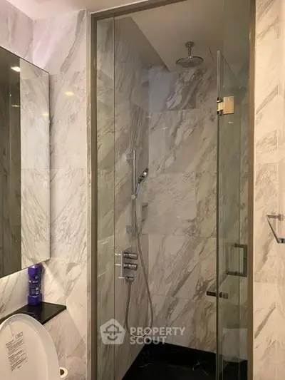 Luxurious marble bathroom with glass shower enclosure and modern fixtures.