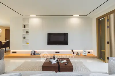 Modern living room with sleek design, built-in shelves, and wall-mounted TV.