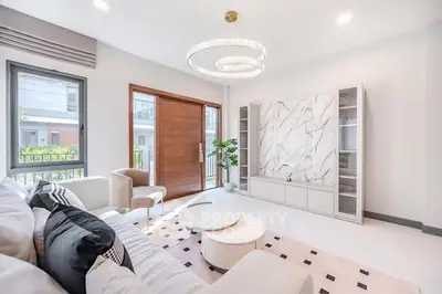 Luxurious modern living room with elegant chandelier and marble accent wall.