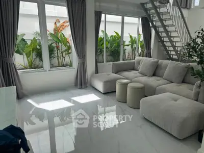 Modern living room with large windows and stylish furniture, featuring a lush garden view.