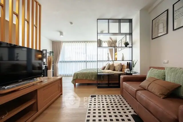 Modern open-plan living room with stylish decor and cozy bedroom area, perfect for urban living.