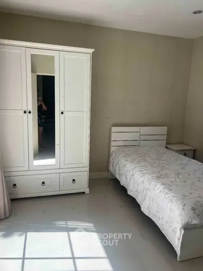 Cozy bedroom with white wardrobe and single bed, perfect for minimalist living.