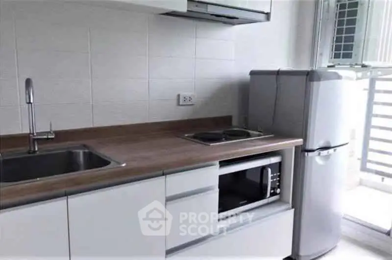 Modern kitchen with sleek appliances and wooden countertop in a bright apartment.