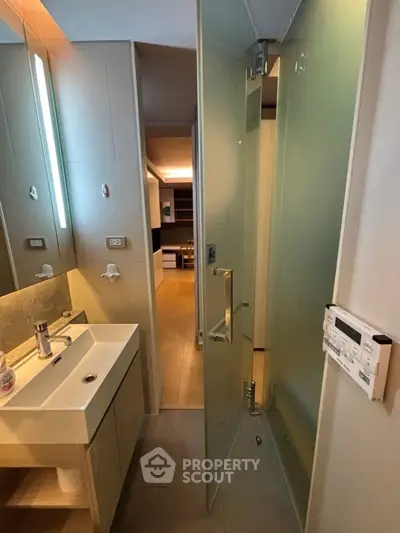 Modern bathroom with sleek design and frosted glass door leading to living area.