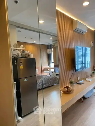 Modern living room with stylish wood paneling and sleek appliances in a cozy apartment.