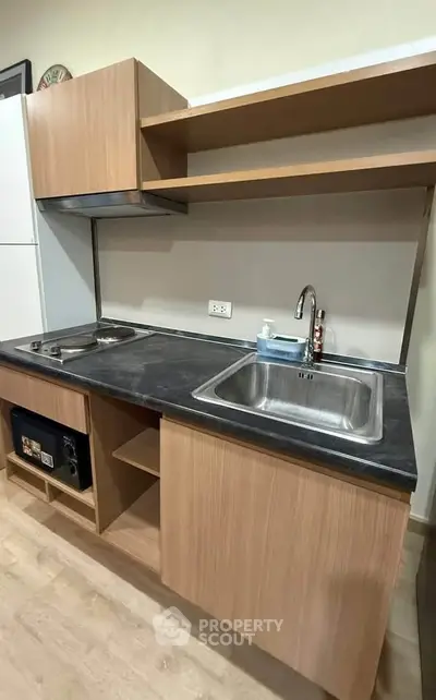 Modern kitchen with sleek wooden cabinets and dual sinks, featuring a compact gas stove and ample counter space.