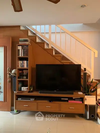 Modern living room with stylish TV unit and staircase, perfect for cozy family gatherings.