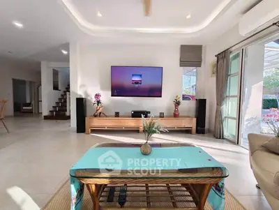 Spacious living room with modern decor and large TV, perfect for relaxation and entertainment.