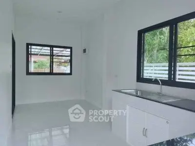 Bright kitchen with sleek white cabinetry and large windows offering natural light and garden views.