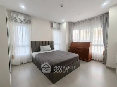 Spacious modern bedroom with large windows and elegant furnishings